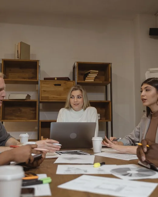A cohort in discussion around a laptop