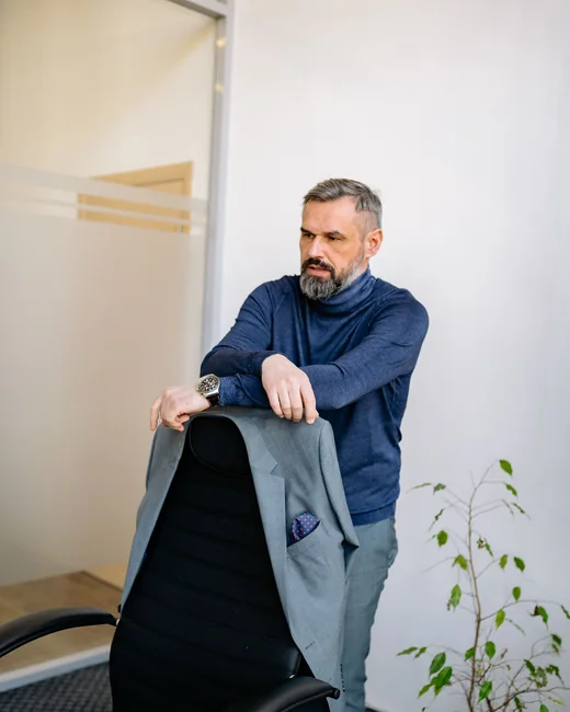 A principal holding a suit jacket over one arm