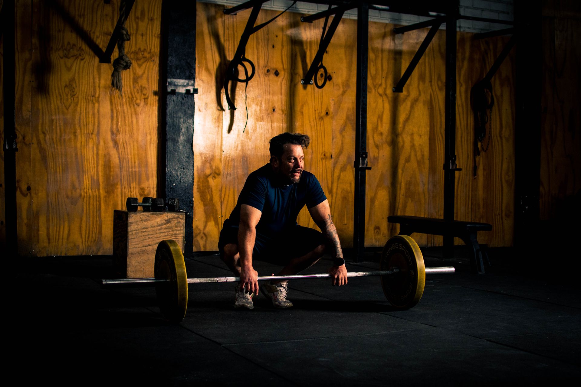 A lifter setting up over a barbell in a dimly lit gym