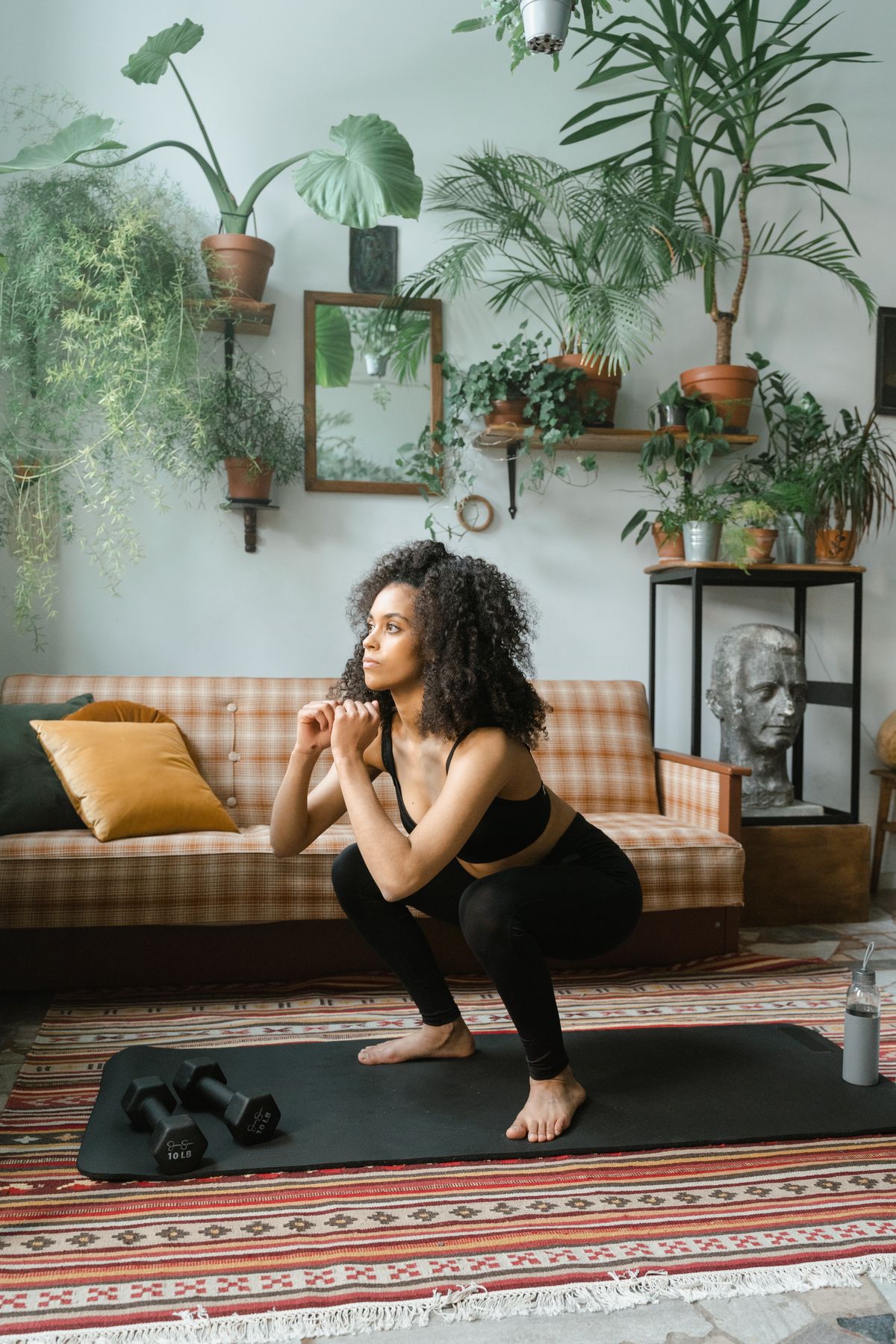 A bodyweight squat at home beside a pair of dumbbells